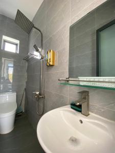 uma casa de banho com um lavatório e um chuveiro com um espelho. em Hotel Vũng Găng em Vinh Hy