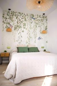 ein Schlafzimmer mit einem weißen Bett mit Vögeln an der Wand in der Unterkunft Casa Rístori Fábrica de Harinas in Manzanares
