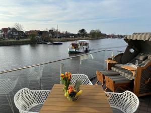 a balcony with a table and chairs and a boat on a river at Seeperle Meerleben in Carolinensiel