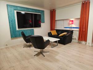 Båtsfjord Royal Hotell في بوتسفيورد: غرفة معيشة مع أريكة وطاولة وكراسي