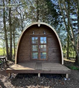 a small wooden cabin with a window in the woods at Woodland camping pod with use of campsite bathroom in Grantham