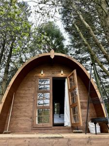 a small house with a large window in the woods at Woodland camping pod with use of campsite bathroom in Grantham