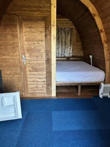 a bed in a wooden room with a door at Woodland camping pod with use of campsite bathroom in Grantham