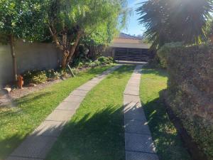 a walkway in a yard with trees and a building at BIRD Song in Hermanus +6 photos