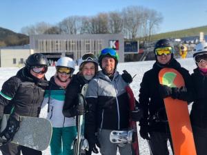 a group of people standing in the snow with snowboards at Chalet BERGgrün Willingen in Willingen