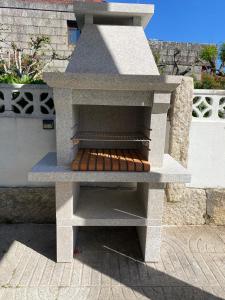 einen Pizzaofen im Freien mit Grill auf einer Terrasse in der Unterkunft Casa con Piscina cerca de la playa in Baiona