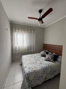 a bedroom with a bed and a ceiling fan at Apto dos Cardeais in Praia Grande
