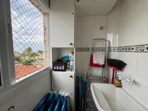 a small bathroom with a sink and a window at Apto dos Cardeais in Praia Grande
