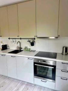 a kitchen with white cabinets and a sink and a stove at Mikro Aparty bezpłatny parking in Wrocław