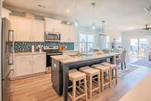 a kitchen with white cabinets and a large island with bar stools at The Bend and Snapper in Carolina Beach