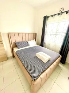 a bed with a blue and white blanket and a window at Pazuri Homes 2BD Apartment in Mombasa