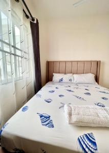 a bed with blue and white sheets and a window at Pazuri Homes 2BD Apartment in Mombasa