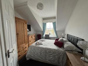 a bedroom with a bed and a dresser and a window at Clarin Guest House in Edinburgh