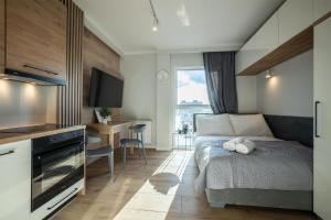ein Schlafzimmer mit einem Bett und einem Schreibtisch sowie eine Küche in der Unterkunft WiguryTower Apartaments 93 in Łódź