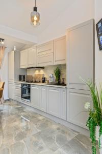 a kitchen with white cabinets and a tile floor at AYASI Luxury Apartment Predeal in Predeal