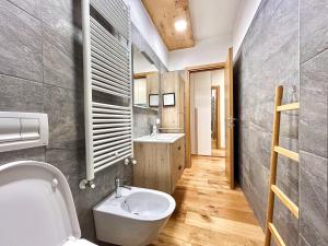 La salle de bains est pourvue de toilettes blanches et d'un lavabo. dans l'établissement Moderno TRILOCALE vicino alle piste, à San Pietro