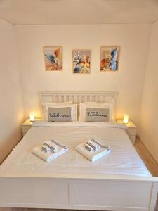 a white bed with two napkins on top of it at Cozy SoRaDa 1 apartment in Bragadiru