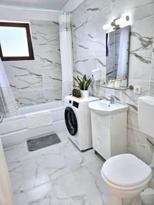 a white bathroom with a toilet and a sink at Cozy SoRaDa 1 apartment in Bragadiru +17 photos