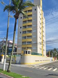 a tall building with a palm tree next to a street at Apto dos Cardeais in Praia Grande