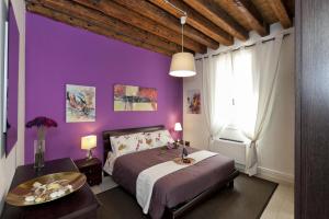 a bedroom with purple walls and a bed and a table at Appartamenti Sofia & Marilyn in Castelfranco Veneto