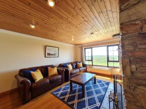 a living room with a leather couch and a table at Sea View Cottage, Errislannan in Ballyconneely