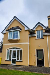 a yellow house with a black door at 15 Killarney Holiday Village in Killarney