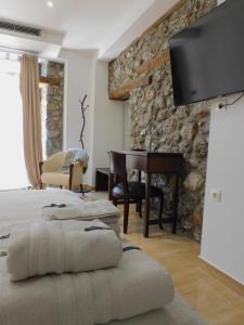 a bedroom with two beds and a desk and a television at Olympus Stone Lodge in Litochoro