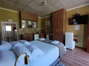 1 Schlafzimmer mit einem großen Bett und einer Küche in der Unterkunft Victoria Oaks Guesthouse in Victoria West