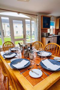 a wooden table with chairs and plates and wine glasses at 15 Killarney Holiday Village in Killarney