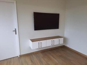 Dieses weiße Zimmer verfügt über einen TV an der Wand. in der Unterkunft Appartement 4 chambres 2 douches in Cergy