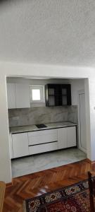 an empty kitchen with white cabinets and a window at Home Nikolić in Novi Pazar