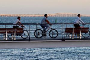 Drei Männer reiten Fahrrad auf einer Brücke über das Wasser in der Unterkunft Casa do Tié in Quinta do Anjo