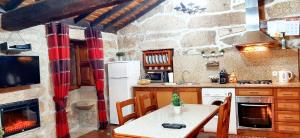 a kitchen with a table and a stove and a fireplace at Charming house in Lindoso with terrace and parking included in Lindoso +18 photos