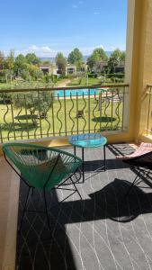 balcón con mesa, sillas y piscina en Résidence du golf en Fez