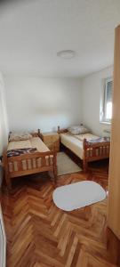 a room with two beds and a wooden floor at Home Nikolić in Novi Pazar
