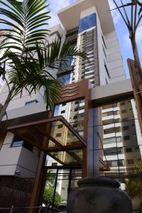 een gebouw met een palmboom ervoor bij Brisas Flat Style in Cuiabá
