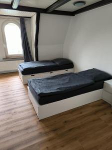 twee bedden in een kamer met houten vloeren en een raam bij Giraffe-1-4-Personen in Brunsbüttel