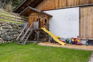 une aire de jeux avec un toboggan et une maison de jeux dans l'établissement Stoffnerhof Apt Sonnenblume, à Monguelfo-Tesido