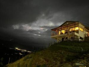 una casa seduta in cima a una collina di notte di La Casita de Charo 1 a Constanza