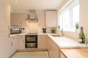 a kitchen with white cabinets and a sink and a window at Stylish 3 Bed, 3 Bath, Garden & Drive for 2 cars in Colne