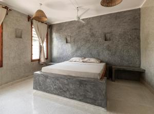 - une chambre avec un grand lit dans un mur en béton dans l'établissement Dolce Vita Watamu Apartments, à Watamu
