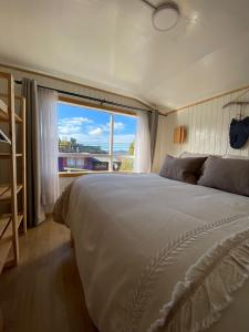 a bedroom with a large bed with a large window at Refugio Ballena Hostel in Castro