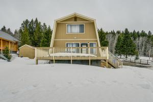 アイランド・パークにあるIsland Park Cabin with Deck about 22 Mi to Yellowstone!の雪の中のデッキ付きの家