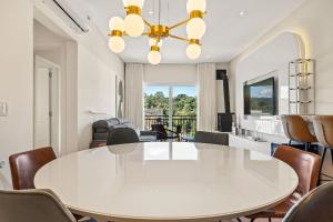 une salle à manger avec une table et des chaises blanches dans l'établissement Apartamento Essence 2 Suítes by Achei Gramado, à Gramado
