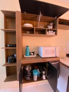 a kitchen with wooden shelves and a microwave at Pousada Vila das Lagoas in Santo Amaro