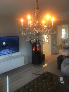a living room with a chandelier and a tv at Villa Skoglund in Stranda