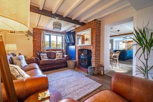 a living room with leather furniture and a fireplace at Ruthie Cottage by Big Skies Cottages in Bacton