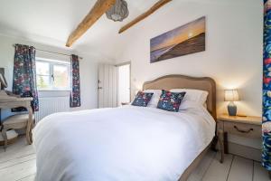 a bedroom with a white bed and a window at Ruthie Cottage by Big Skies Cottages in Bacton