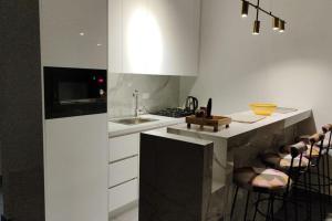 a kitchen with a counter with a sink and some stools at Rita's 2-BR Apt in Mar Mikhael in Beirut