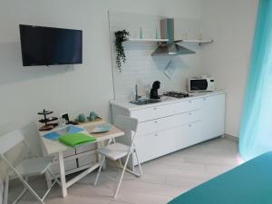 a white kitchen with a table and a microwave at SoleMare Rooms "Smeraldo" in Procida